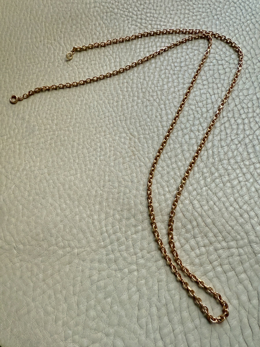 18k Gold chain necklace on a textured light green surface