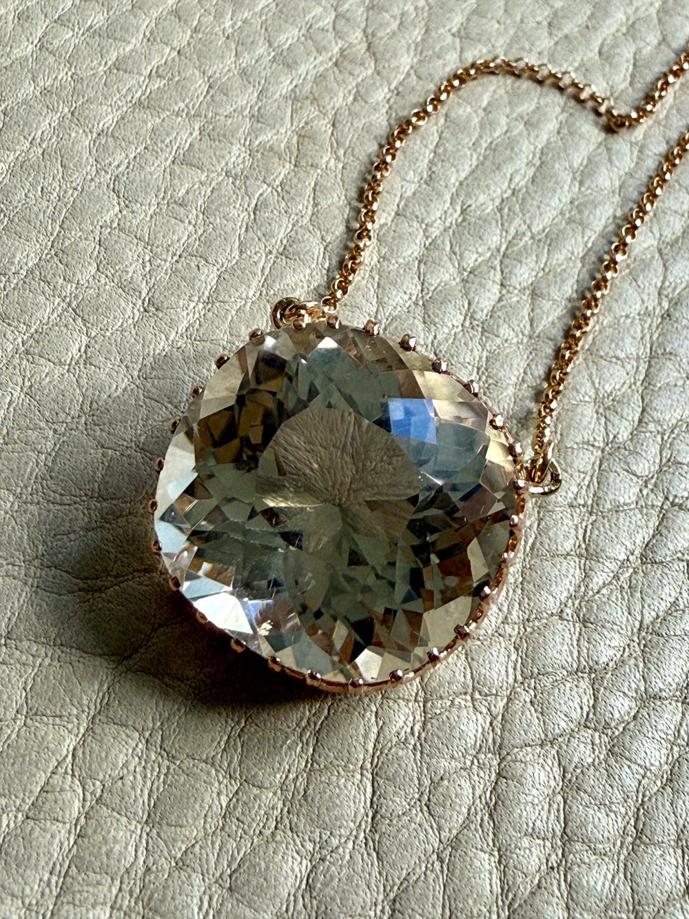 18k gold Necklace with a large, faceted smoky crystal pendant on a textured surface