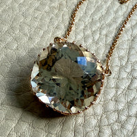 18k gold Necklace with a large, faceted smoky crystal pendant on a textured surface