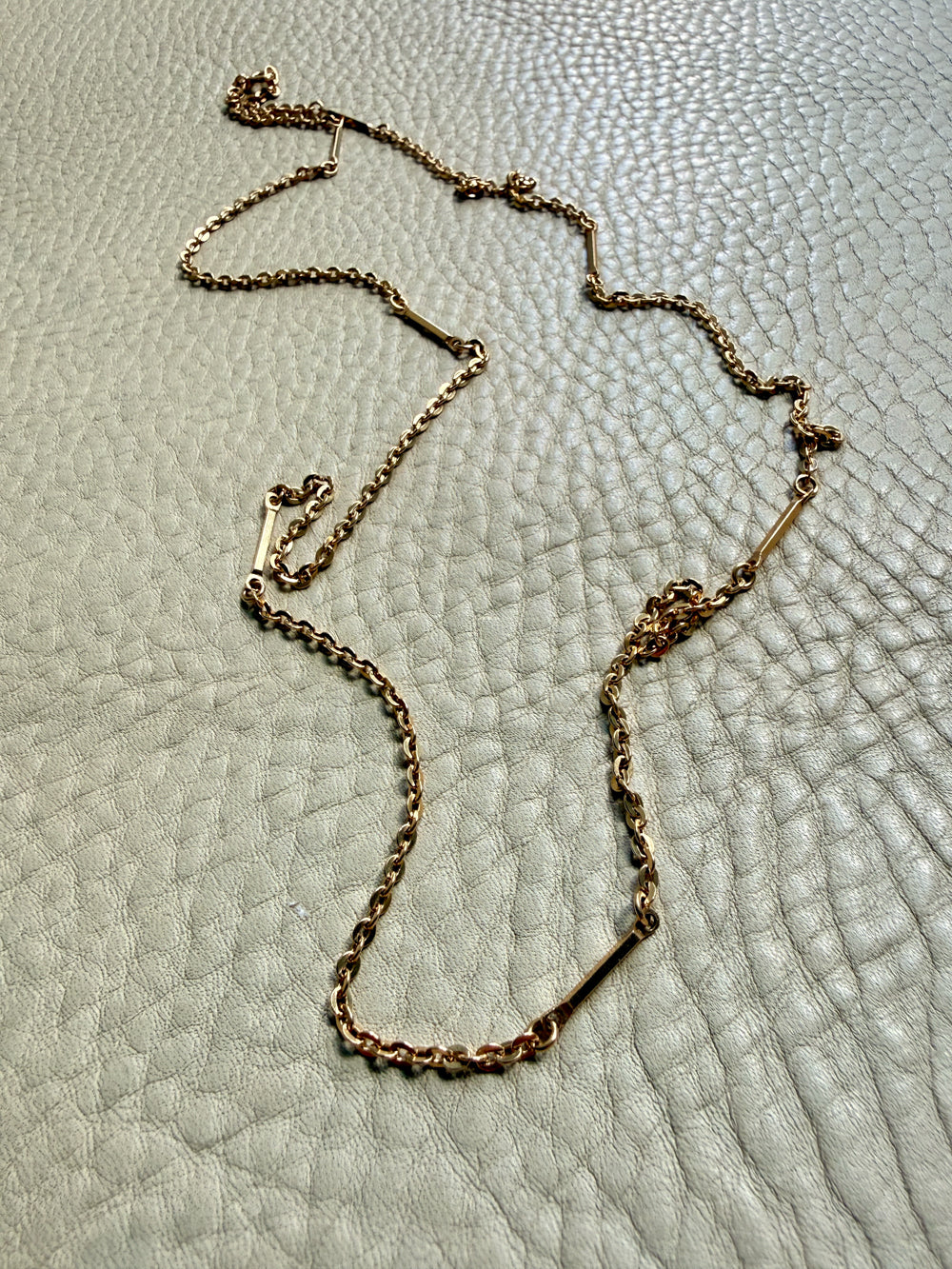 Gold chain necklace on a textured light gray surface