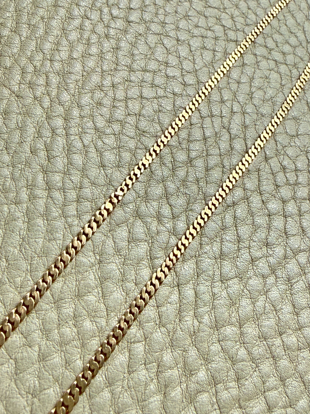 Gold chain on a textured beige leather background