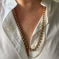 Gold chain necklaces worn by a person in a white shirt.