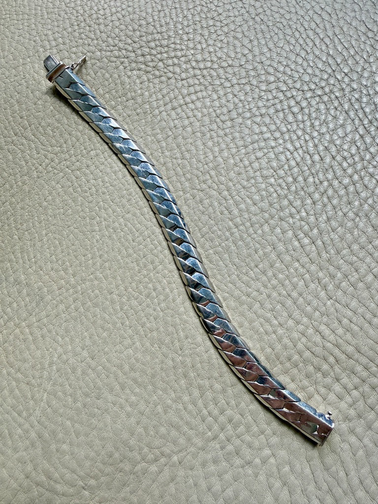 silver bracelet with textured design on a textured surface