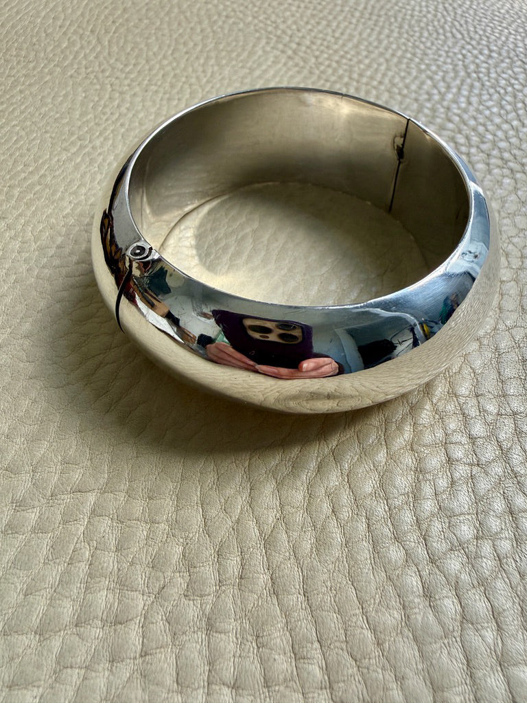 Silver bangle on a textured beige surface