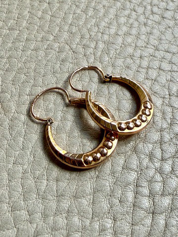 Pair of French vintage 18k Gold hoop earrings on a textured light gray surface