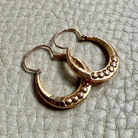 Pair of French vintage 18k Gold hoop earrings on a textured light gray surface