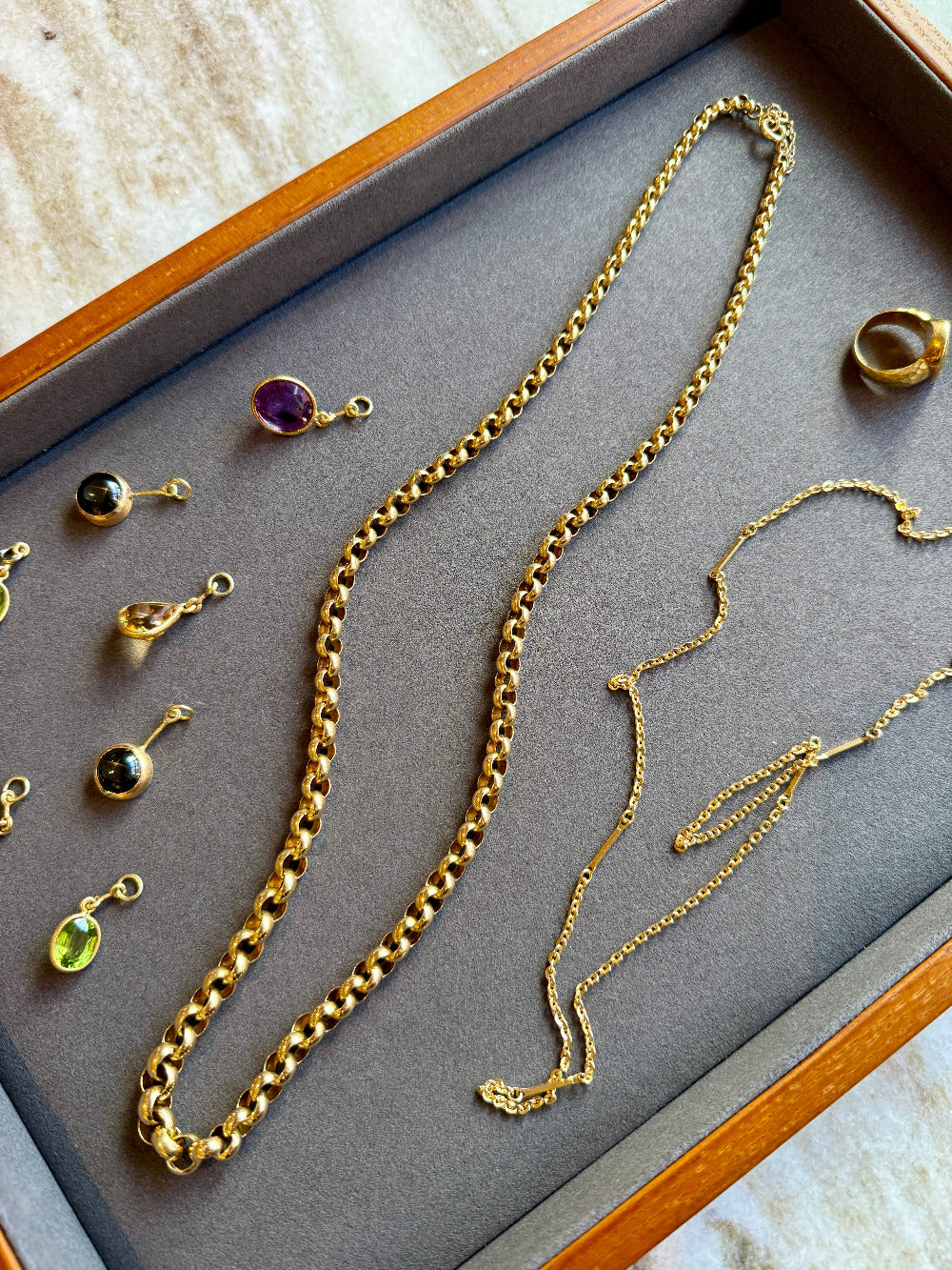 Gold necklaces and earrings on a gray surface with a wooden border.