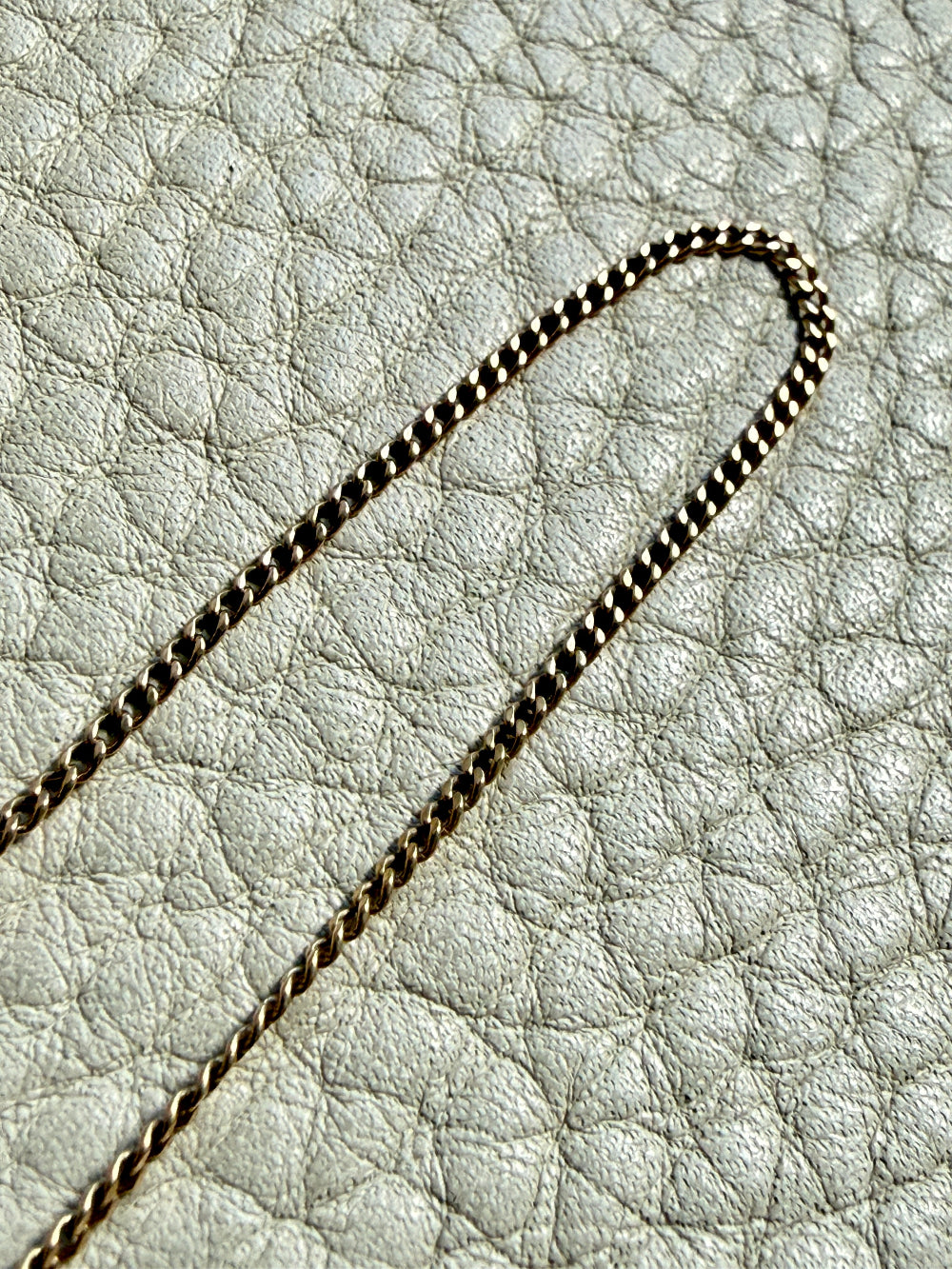 Gold chain on a textured light gray surface