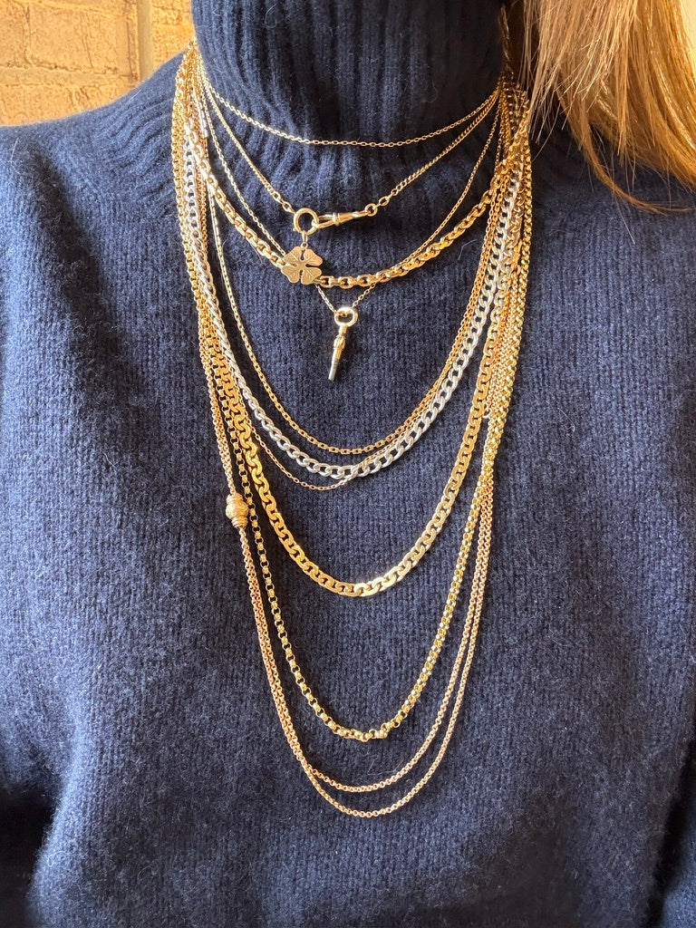 Gold necklaces on a person wearing a blue sweater