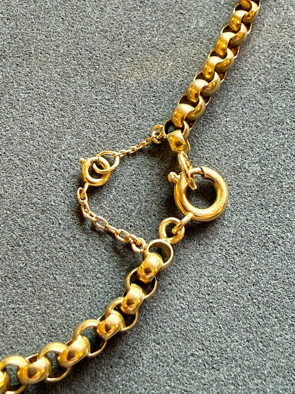 Gold chain necklace on a textured gray surface