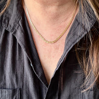 Person wearing a gold necklace with a gray shirt