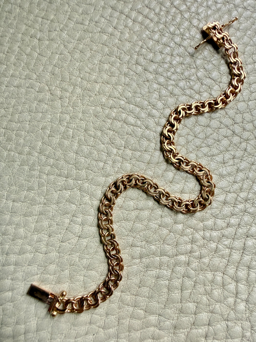 18k Gold chain bracelet on a textured light green surface