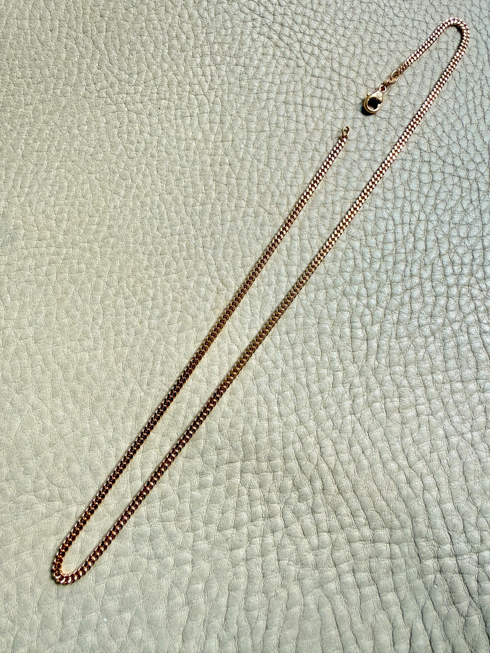 Gold chain necklace on a textured light gray background