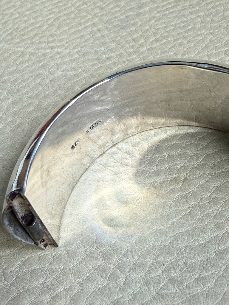 Close-up of a silver bracelet on a textured beige surface