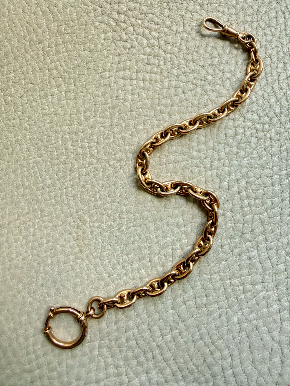 18k gold antique watch chain on a textured light green background