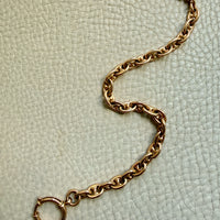 18k gold antique watch chain on a textured light green background