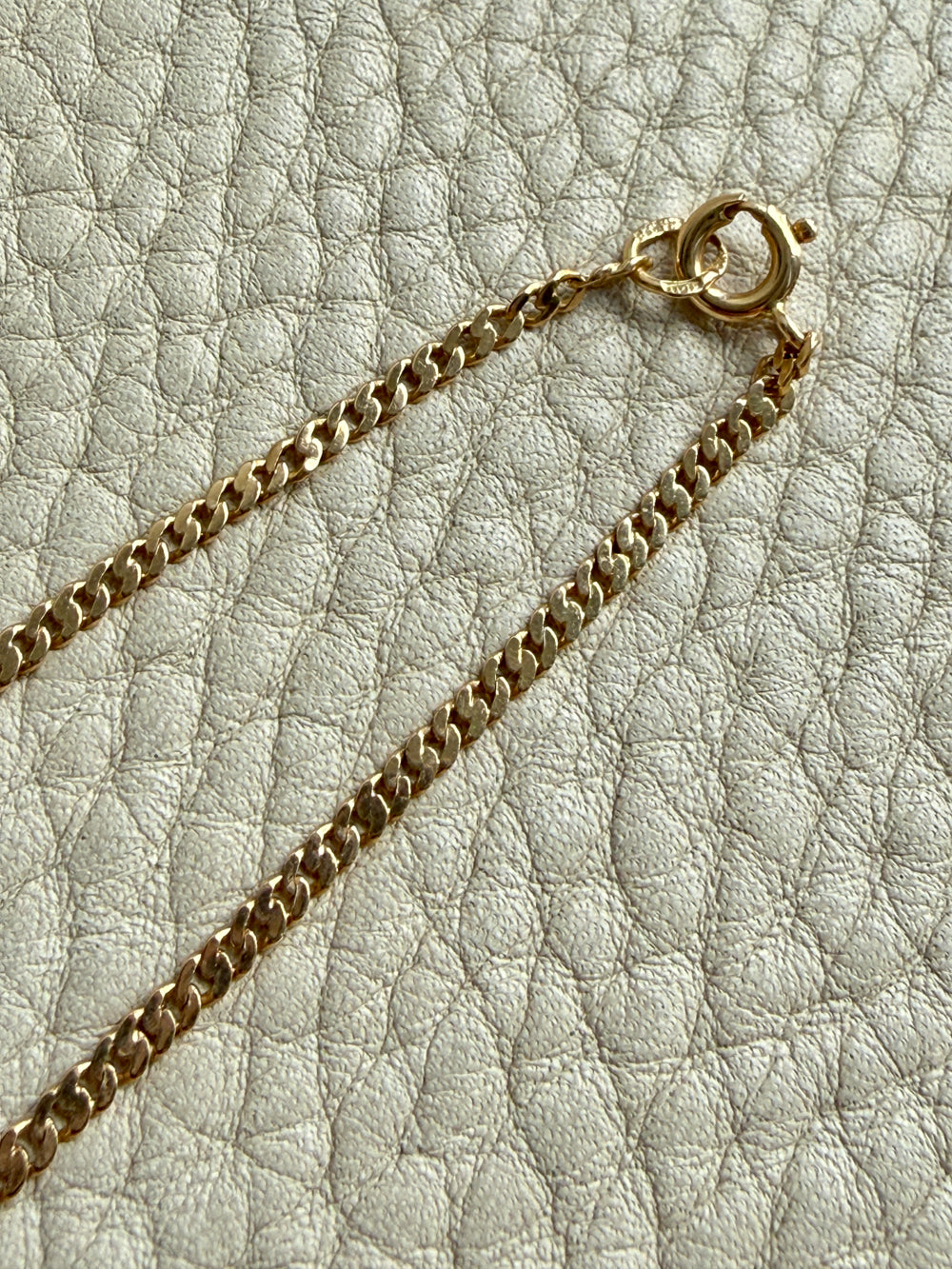 Gold chain necklace on a textured light gray surface