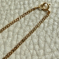 Gold chain necklace on a textured light gray surface