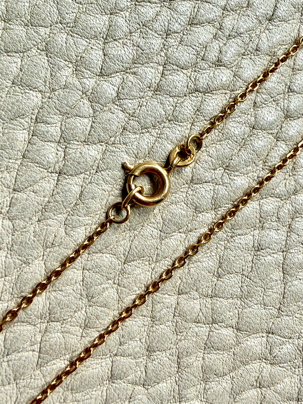 Gold chain necklace on a textured light gray surface