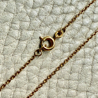 Gold chain necklace on a textured light gray surface