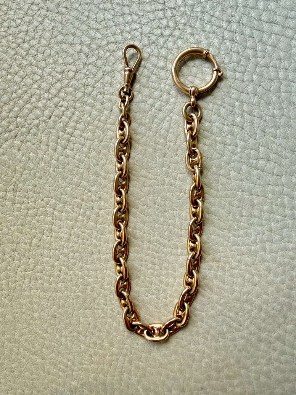 18k gold antique watch chain necklace on a textured light gray background