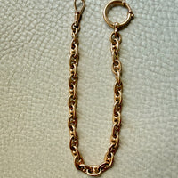 18k gold antique watch chain necklace on a textured light gray background