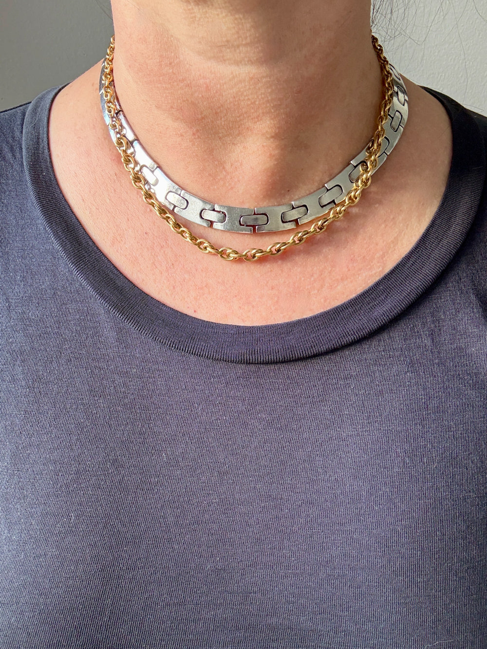 Two necklaces, one gold and one silver, draped on a neck