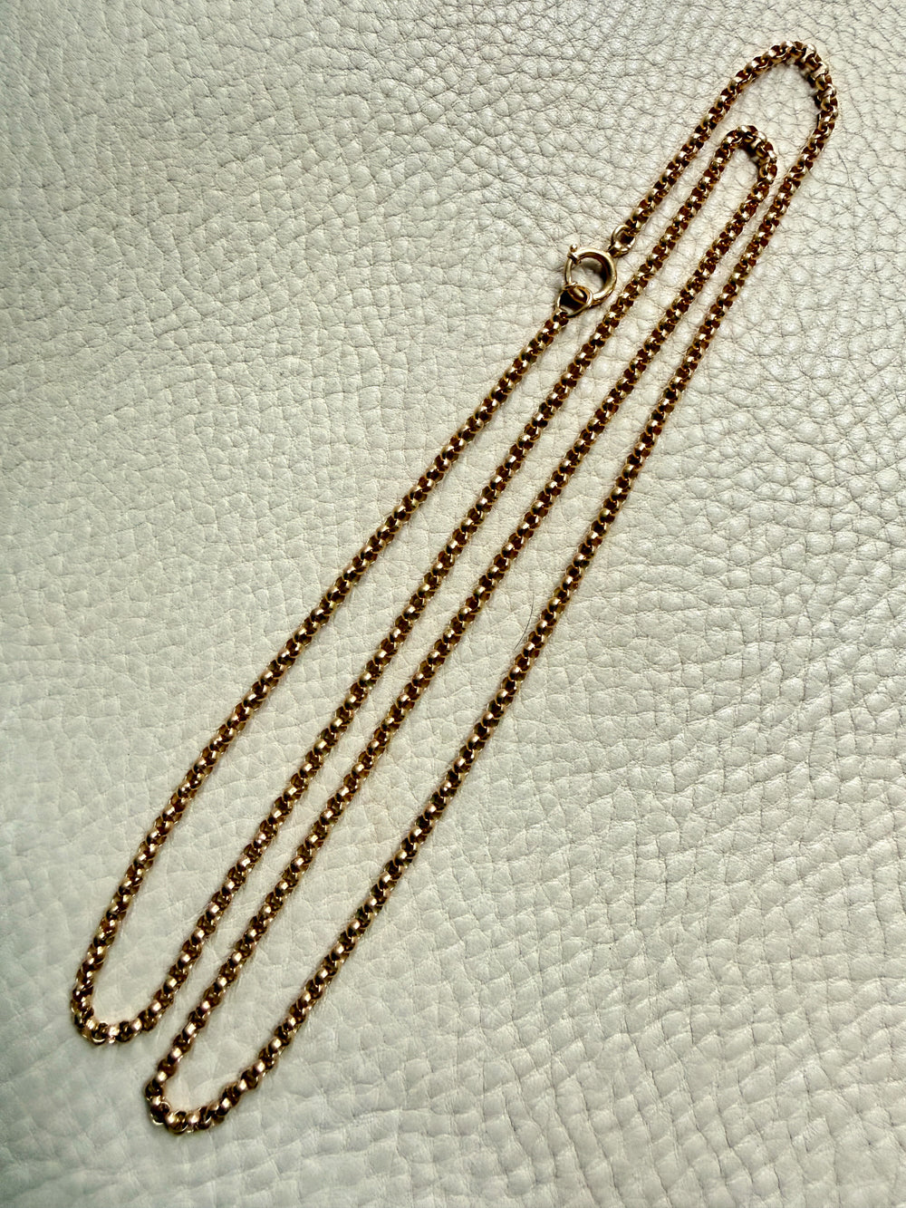18k Gold antique rolo link necklace on a textured light gray surface
