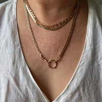 Person wearing a gold chain necklace on a plain background. PenelopePenelope.com