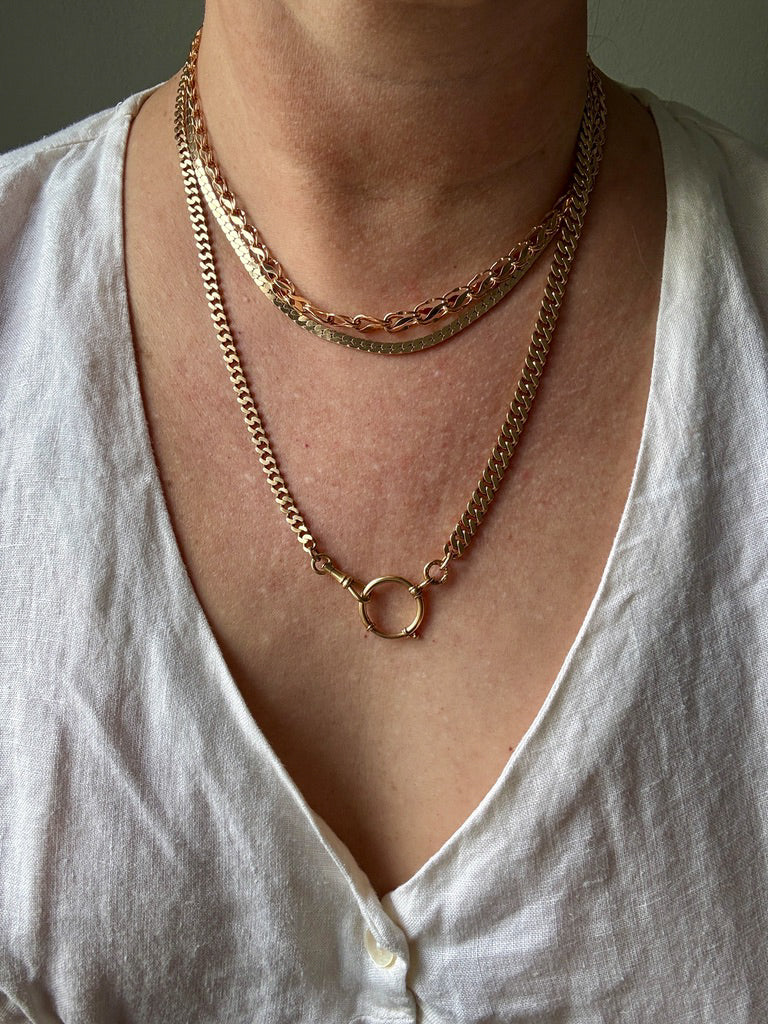 Person wearing a gold chain necklace on a plain background. PenelopePenelope.com