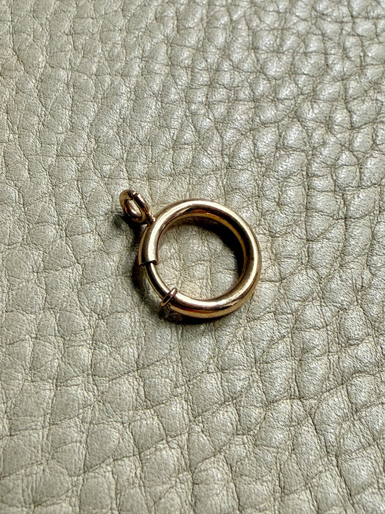 large gold bolt clasp on a textured beige surface PenelopePenelope.com 