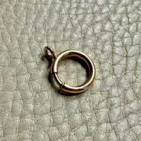 large gold bolt clasp on a textured beige surface PenelopePenelope.com 