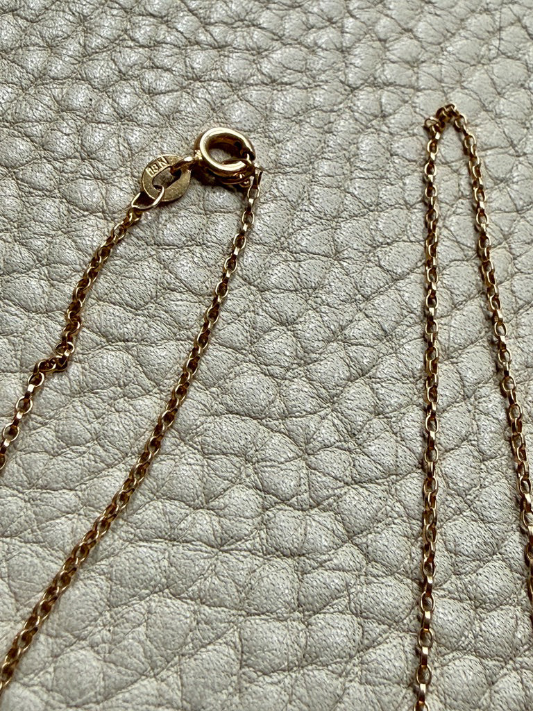 Close-up of a gold chain necklace on a textured light gray surface