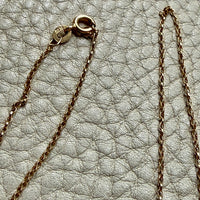 Close-up of a gold chain necklace on a textured light gray surface