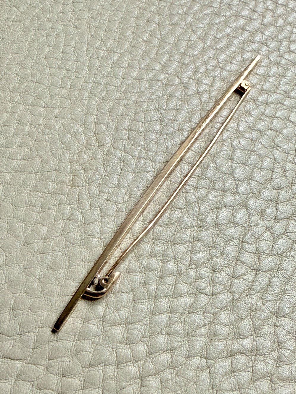 18k gold antique brooch on a textured beige background