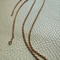 antique gold chain necklace on a textured light gray background

