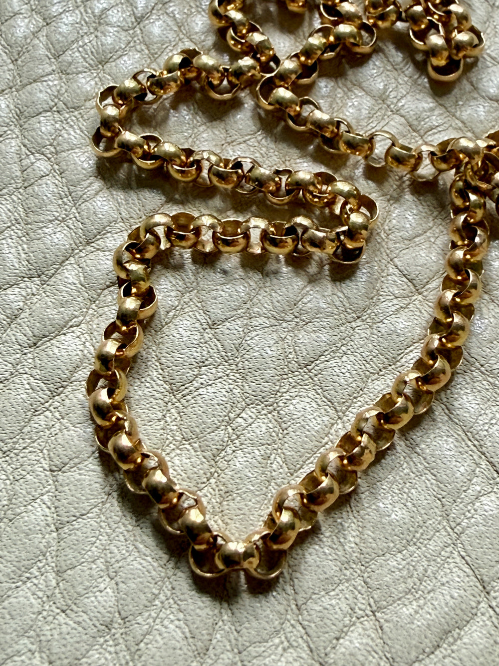 Gold chain on a textured beige surface
