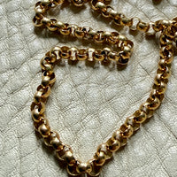 Gold chain on a textured beige surface
