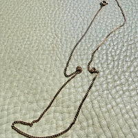 18k gold curb Necklace with a clasp on a textured light gray surface
