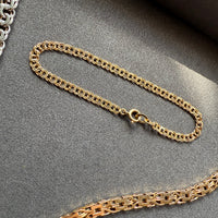 Gold chain bracelet on a gray surface