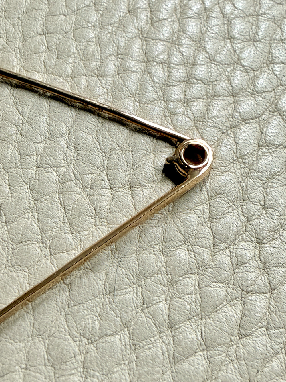Close-up of a gold brooch on a light gray textured background