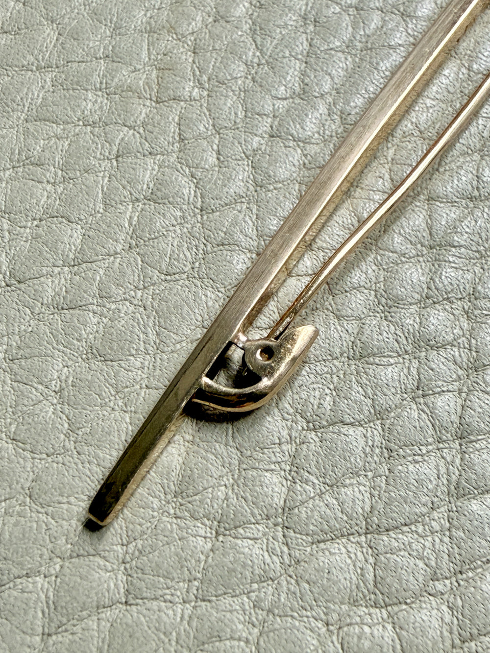 Close-up of a 18k gold antique brooch on a textured beige background