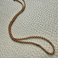 18k gold vintage rolo chain necklace on a textured light gray surface