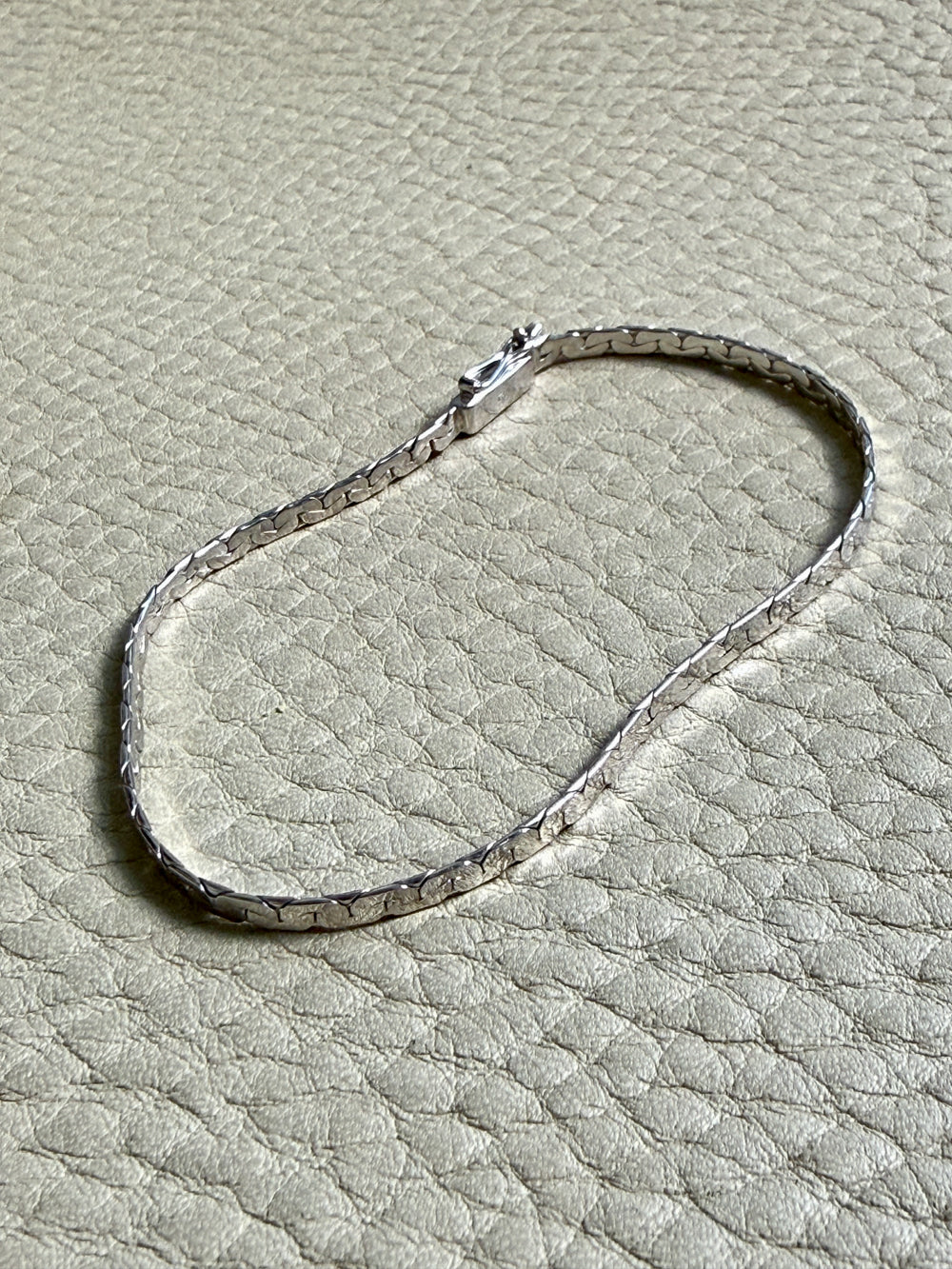 14k white gold bracelet on a textured beige surface
