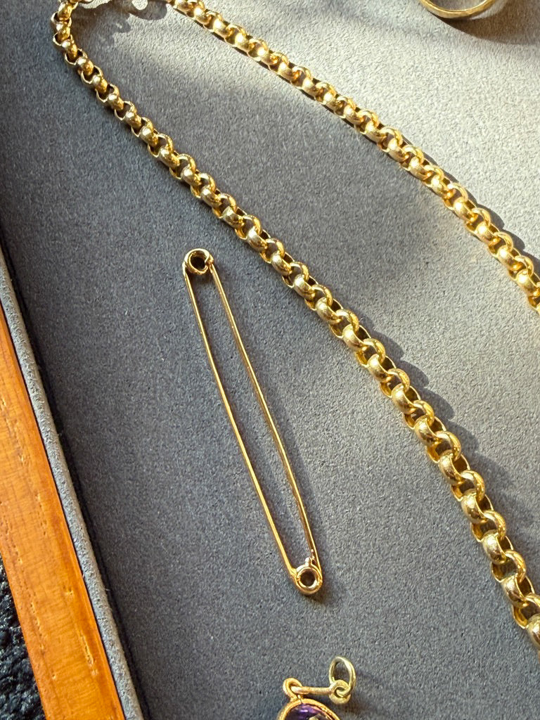 Gold chain and brooch on a gray surface