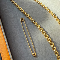Gold chain and brooch on a gray surface