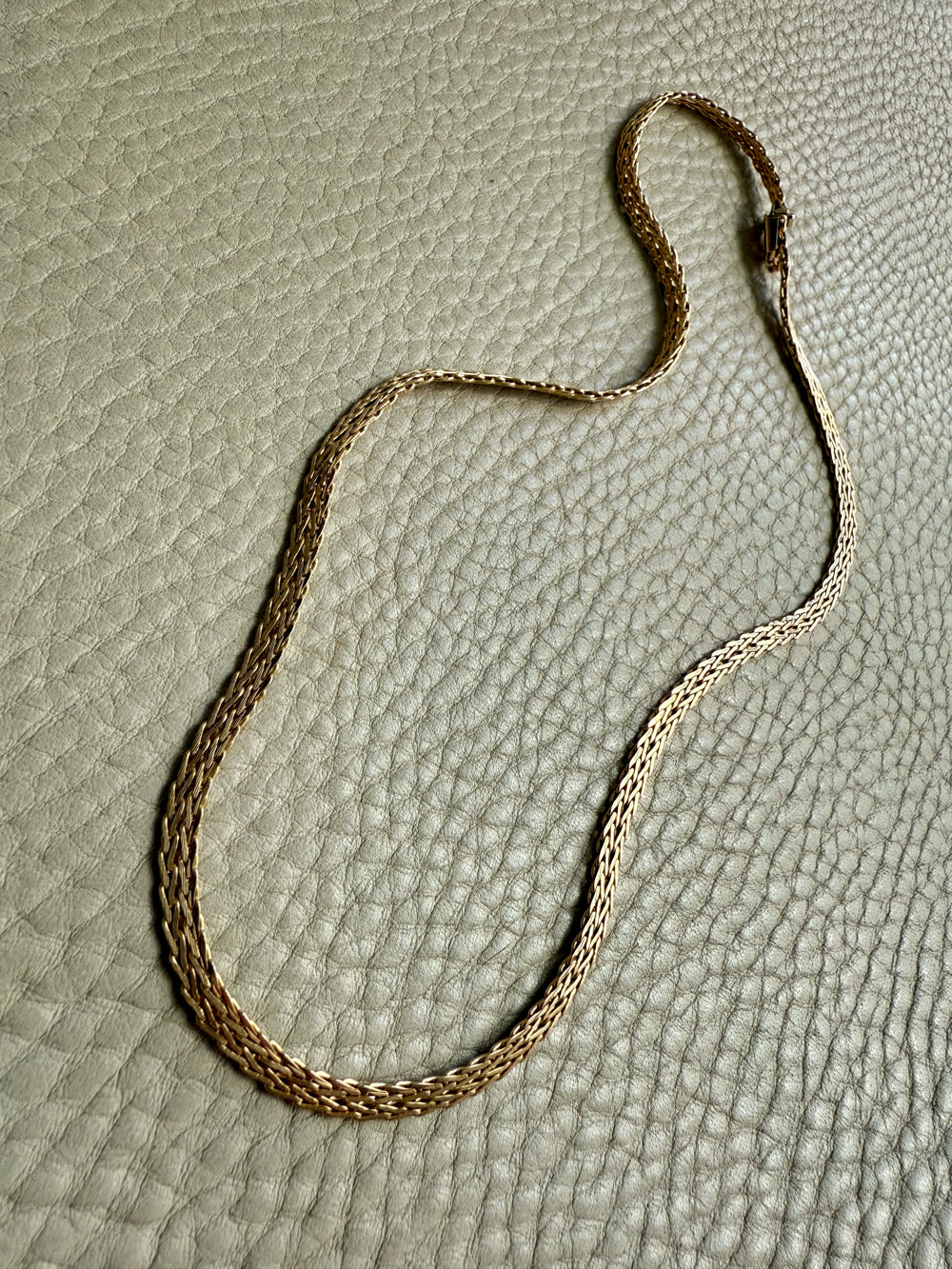 Gold chain necklace on a textured beige surface
