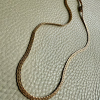 Gold chain necklace on a textured beige surface