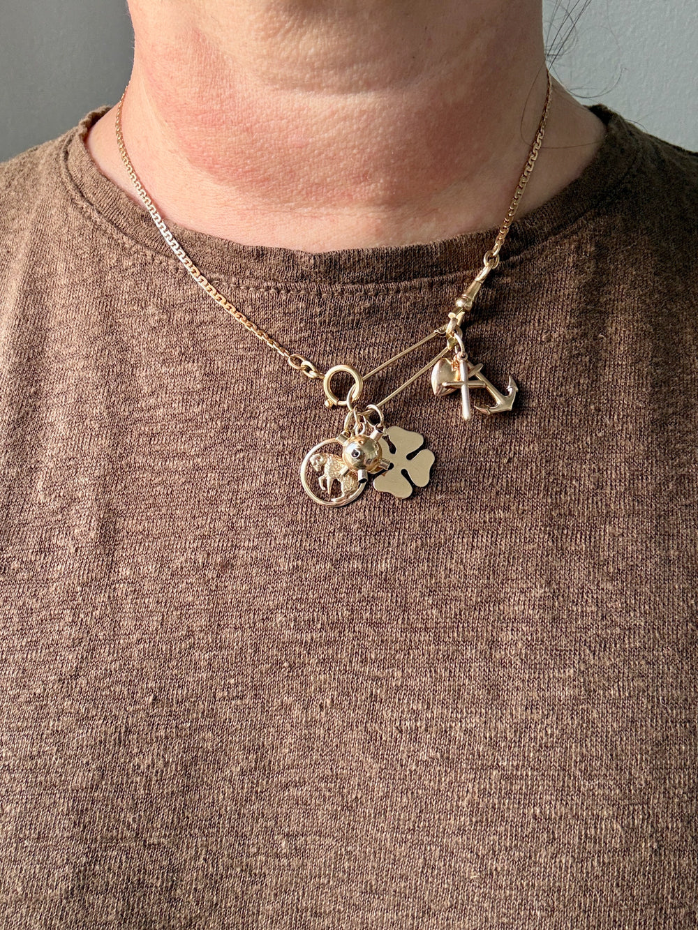 Gold necklace with charms worn by a person against a neutral background