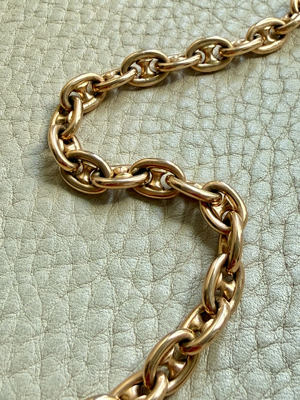 18k gold antique watch chain on a textured light green surface